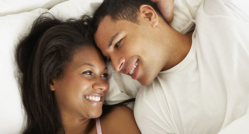 couple in bed smiling at each other