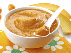 Bowl of pureed carrot and pumpkin with a baby spoon on top