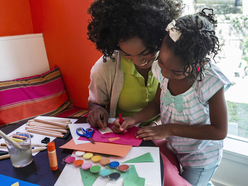 Mum and daughter playing with crayons and paper scraps