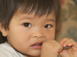 Toddler chewing on a spoon.