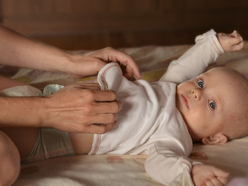mum changing a baby's nappy on a change table