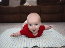 baby doing tummy time with arms stuck out and smiling