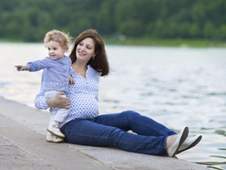pregnant mum with a toddler sitting next to a lake