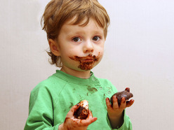 A toddler eating chocolate biscuits