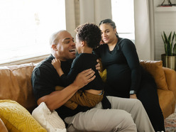 Dad and pregnant mum on sofa playing with toddler