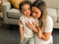 Mum comforting upset toddler in living room