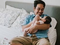 Man smiling and feeding a baby with a bottle