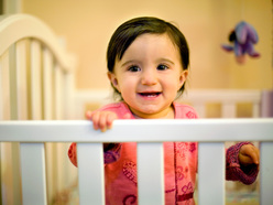 Toddler standing in cot smiling