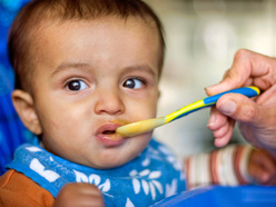 Baby being spoonfed fruit puree