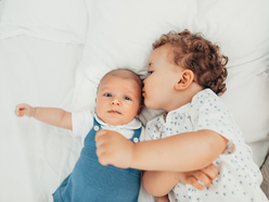 Toddler kissing baby brother on the cheek