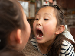 Little girl looking at open mouth in mirror