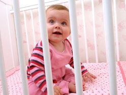 Baby sitting up awake in her cot
