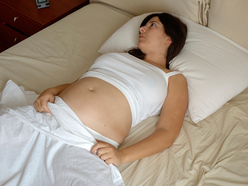 Pregnant woman lying on her back in bed