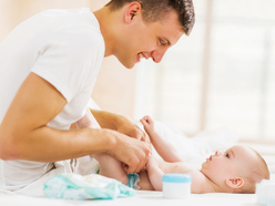 a dad changing his baby's nappy on a change table