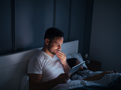 Man using tablet in bed at night