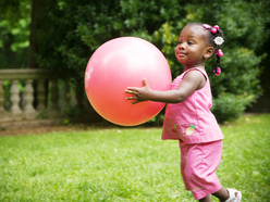 Toddler running while holding a giant ball