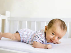 young baby doing tummy time in her cot