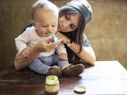 a woman feeds a baby from a spoon