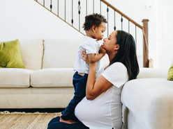 Pregnant mum kissing and comforting toddler