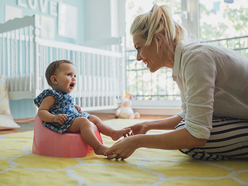 Mum helping little girl on potty