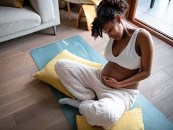 Pregnant woman sitting on a yoga mat and cradling her belly
